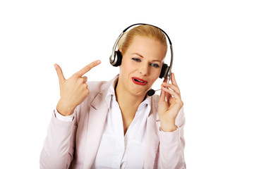 Happy female phone operator pointing at headphones