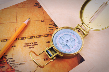 Pencil, compass and vintage map on a wooden table.