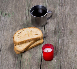 coffee in a steel mug, three croutons and the burning candle