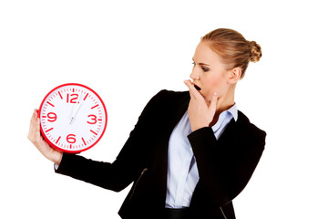 Yawning business woman holding office clock