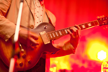 Musician plays on guitar in grey jacket