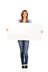 Happy teenage woman with blank billboard