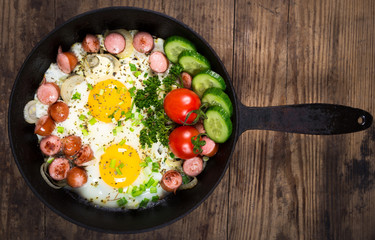 fried egg and sausage in the pan on wooden background