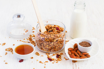 Healthy breakfast - granola, almonds, milk and honey on a white 