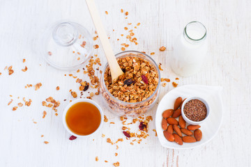Healthy breakfast - granola, almonds, milk and honey on a white 