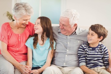 Grandparents and grandchildren sitting together on sofa