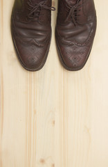 Male brown leather shoes on wooden background, flat lay
