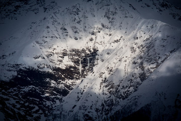 topview to Caucasian mountains covered by snow and cloud shadows  