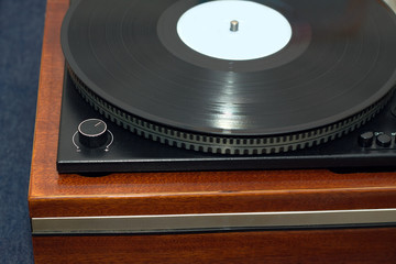 Part of vintage classic record player in wooden case with black LP vinyl record front view...