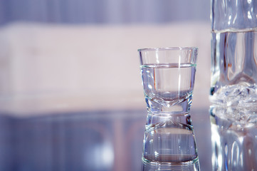 vodka glass / A vodka glass with a bottle standing on the glass table
