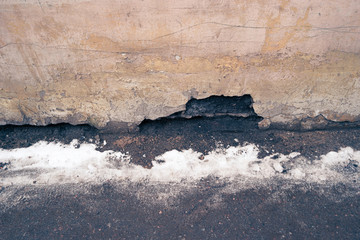 Weathered background, empty grunge urban street with snow and obsolete wall. 