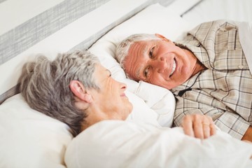 Happy senior couple smiling in bed