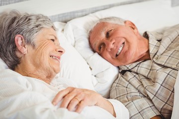 Happy senior couple smiling in bed