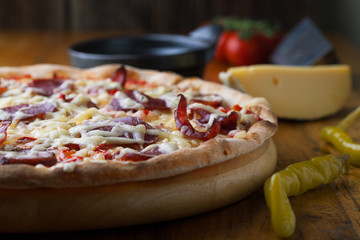 Delicious pizza with salami, tomatoes and hot peppers