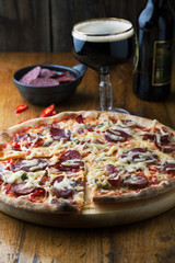 Delicious pizza with salami, tomatoes and dark beer