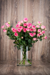 Roses in the vase on wooden background
