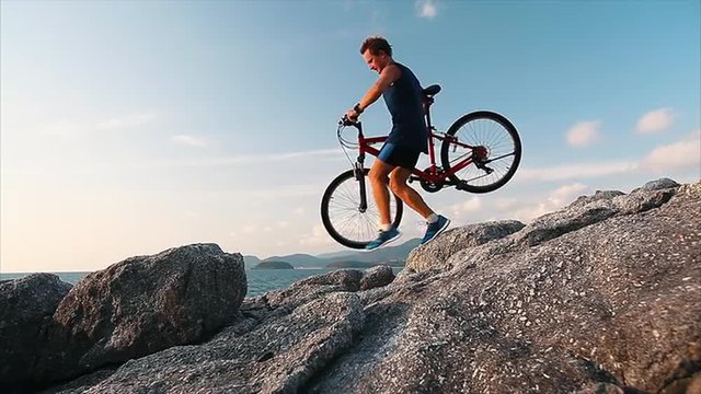 Man walks with bicycle on the rocky terrain