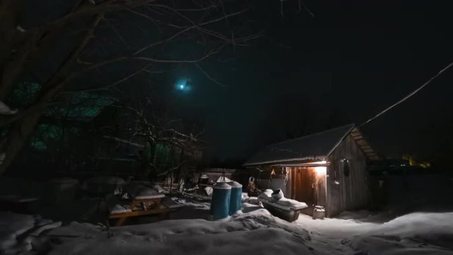 Time lapse of the winter garden with wooden building illuminated by lamp. Day to night to day loopable sequence.