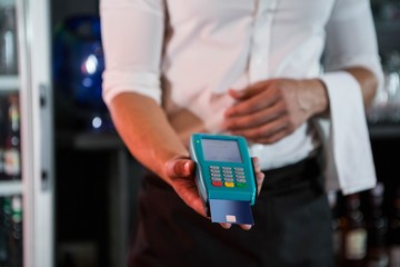 Bartender accepting a credit card at bar counter