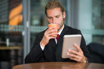 Businessman using his tablet computer in a cafe