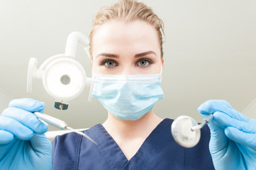 Beautiful woman dentist holding dental tools being ready for exa