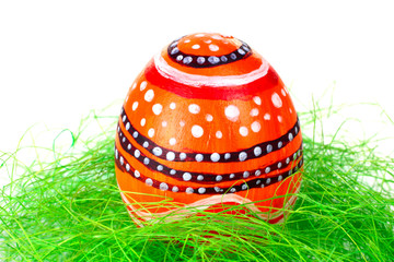 Easter egg in a beautiful and different colours lying on the grass on a white isolated background
