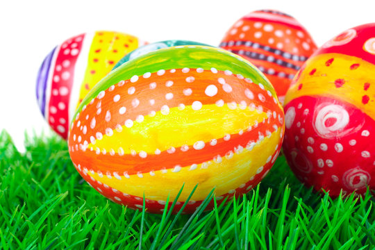 Easter eggs in beautiful and different colors lie on the grass on a white isolated background