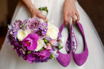 Bride holding shoes and colorful bouquet