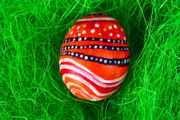 Easter egg in a beautiful and different colours lying on the grass closeup