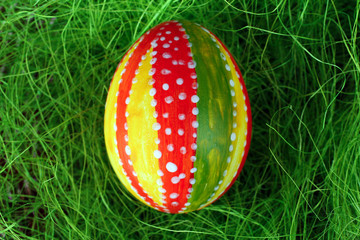 Easter egg in a beautiful and different colours lying on the grass closeup