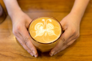 close up of hands with latte art in coffee cup