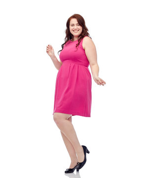 happy young plus size woman dancing in pink dress