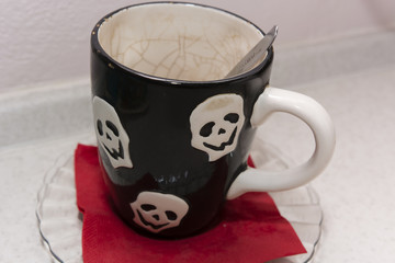 old used a mug decorated with skulls and spoon