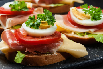 Delicious sandwich with prosciutto ham, cheese, tomato and egg