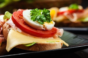 Delicious sandwich with prosciutto ham, cheese, tomato and egg