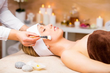 Beautiful young woman getting facial mask