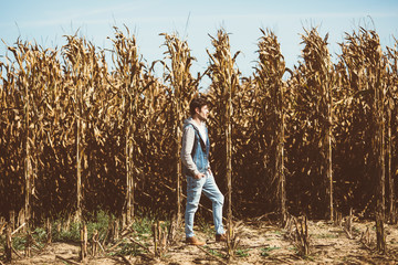 Young bearded man standing in the middle of cornfield