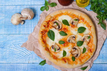 Italian food. Mediterranean cuisine. Delicious pizza with mushrooms and basil - thin pastry crust on wooden background.