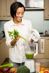 Smiling brunette preparing smoothie