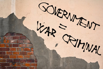Handwritten graffiti Government Is War Criminal sprayed on the wall, anarchist aesthetics 