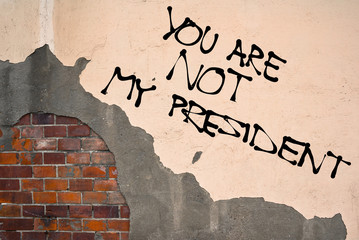 Handwritten graffiti You Are Not My President sprayed on the wall, anarchist aesthetics 