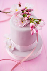 Fototapeta na wymiar Pink cake decorated with fondant and cherryblossoms