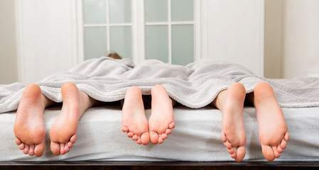 Feet of a family in bed 