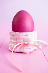 Pink Easter egg wrapped ina pink napkin and decorated with a satin ribbon