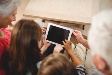 Children using tablet with their grandparents