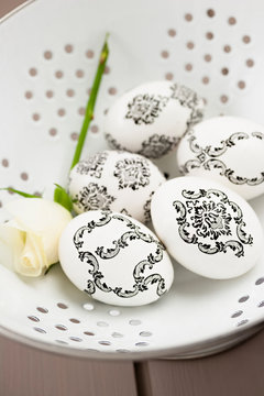 White Easter egg decorated with baroque decoupage with rose in a strainer