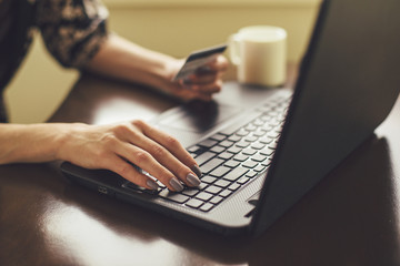 Female holding credit card and typing on laptop