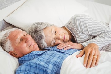 Senior couple sleeping on bed