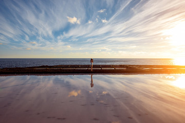 Volcanic pool with woman standing on the salt manufaturing with pink salt water and reflection on La Palma island