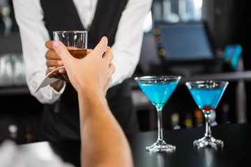 Bartender serving whiskey at bar counter